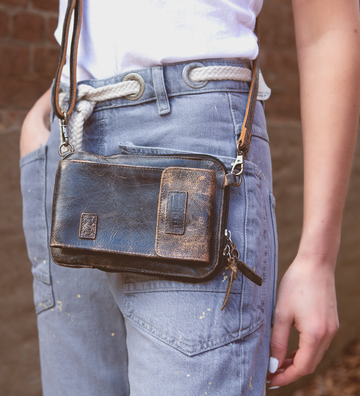 A woman wearing jeans and a Bed Stu Alelike premium leather crossbody bag.