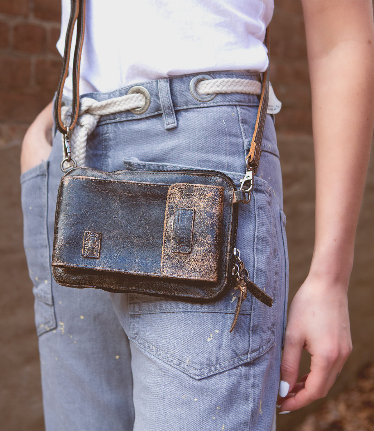 A woman wearing jeans and a Bed Stu Alelike premium leather crossbody bag.