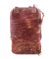 The Bed Stu Alelike is a compact brown leather pouch featuring visible creases, metal rivets, a top zipper, and a small side strap, shown against a white background.