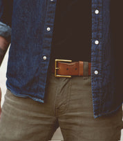 Person wearing a blue denim shirt, beige pants, and a brown leather belt with a removable metal buckle named Alex by Bed Stu. The image is cropped to show only the torso and upper legs.