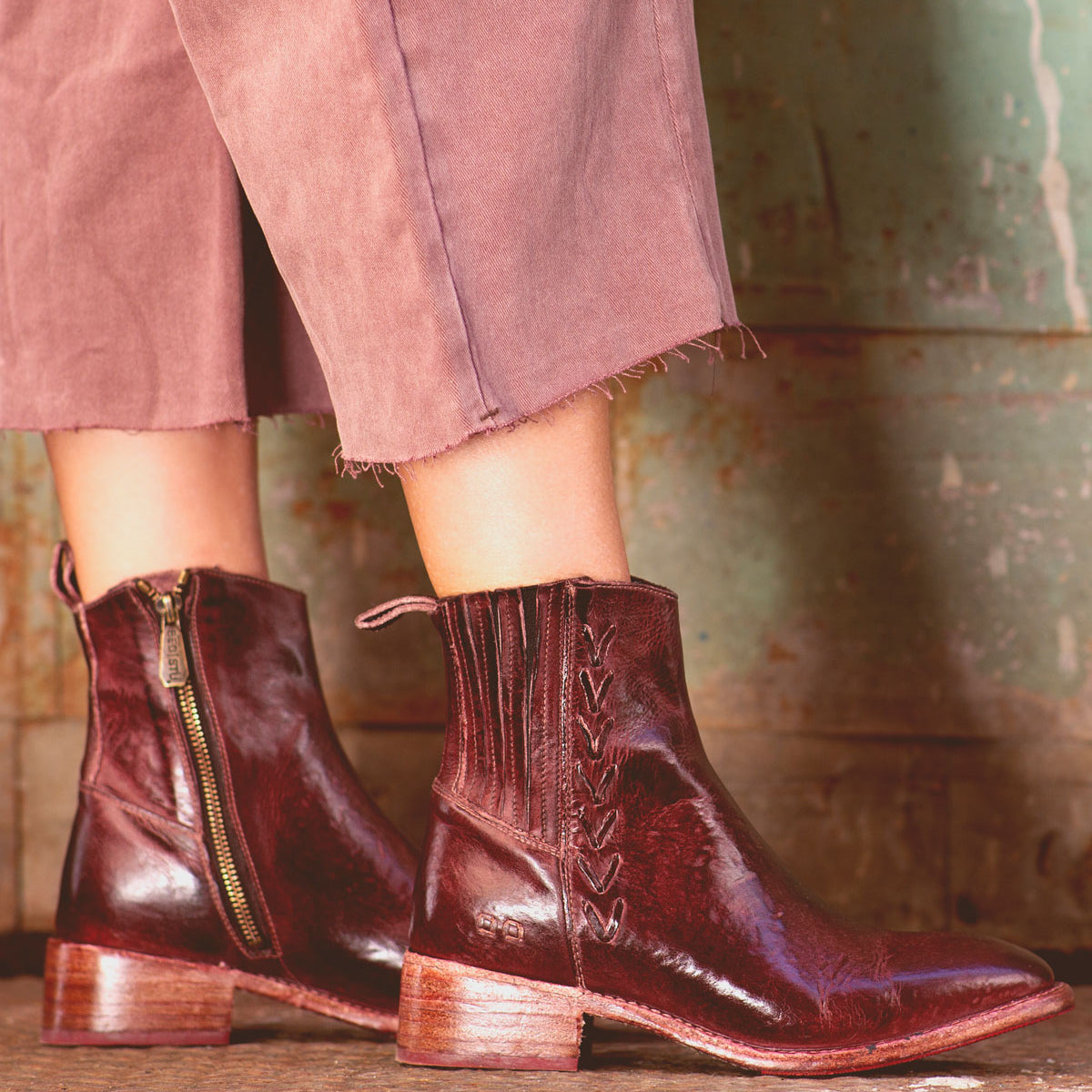 A woman wearing a pair of Bed Stu Alina burgundy leather ankle boots in the city.
