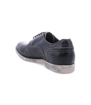 The Bed Stu Anchiano is a black leather oxford shoe with distressed leather, visible stitching, a worn sole, and shown from the back left side for a timeless look.