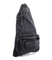 The Andie by Bed Stu is a black, triangular-shaped leather sling bag featuring multiple zippered compartments and an adjustable strap, offering practical functionality for everyday use as a versatile accessory.