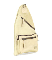 The Andie by Bed Stu is a versatile beige leather crossbody sling bag with two zippered compartments and a sleek metal ring at the top, offering practical style for any occasion.