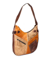 The Bed Stu Argus is a patchwork leather bag featuring oversized front pockets—a zippered pocket and a small stitched pocket—and a two-tone brown adjustable strap.