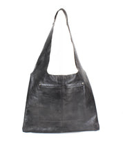 The Bed Stu Ariel II is a large black leather shoulder bag with a front pocket and wide strap, showcasing minimalism with a spacious compartment. It is displayed against a plain white background.