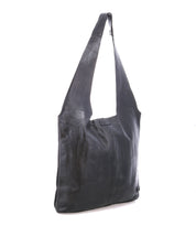 The Bed Stu Ariel Max is a black hand-finished leather shoulder bag with a long, wide strap and rectangular shape, featuring a spacious interior. Photographed against a white background.