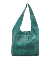 The Bed Stu Ariel Max is a teal artisanal bag with hand-finished leather, a wide strap, and a large external front pocket, shown standing upright against a white background.