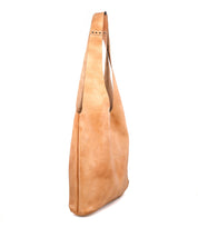 The Bed Stu Ariel Max is a hand-finished leather tote with a single wide shoulder strap, shown standing upright against a white background. This oversized bag highlights artisanal craftsmanship and timeless style.