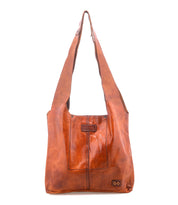 The Bed Stu Ariel Mid is a brown artisanal handbag crafted from full-grain leather, featuring a wide strap, rectangular shape, and visible front stitching.