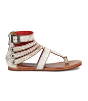 The Bed Stu Artemis II is a flat, open-toe gladiator sandal with metallic leather straps, an ankle buckle, side zipper, and wooden sole, shown in a side view.