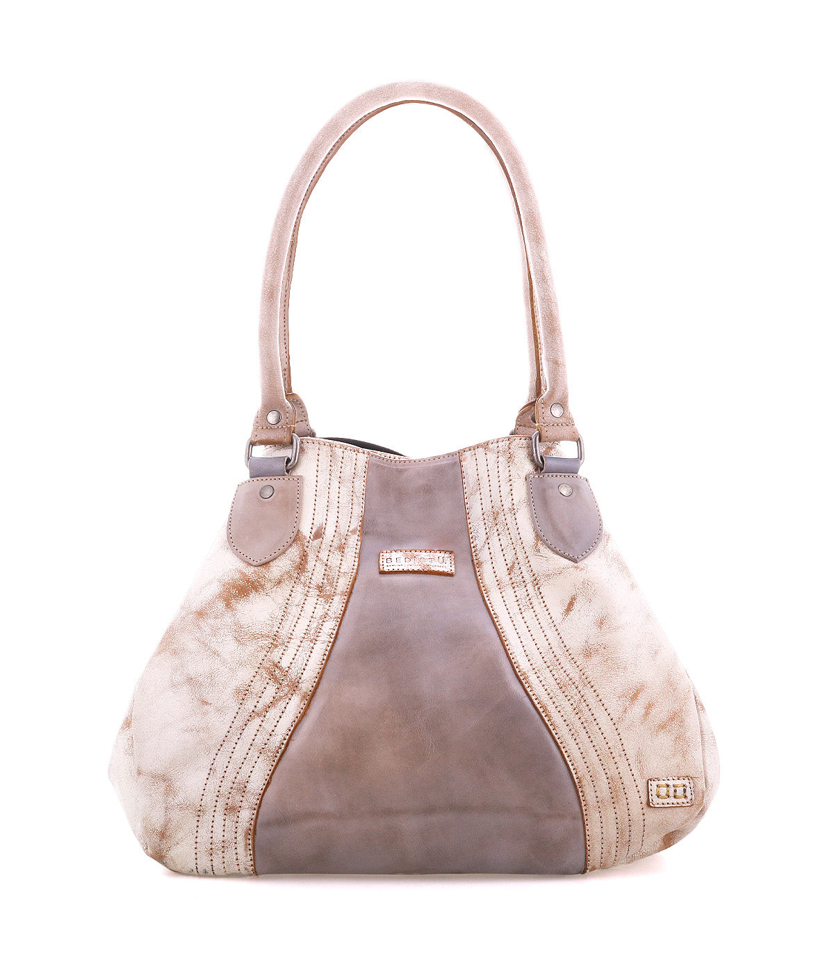 The Bed Stu Astana is a modern beige and taupe handbag featuring two handles, decorative stitching, and a metallic logo on the lower right corner, displayed against a white background.