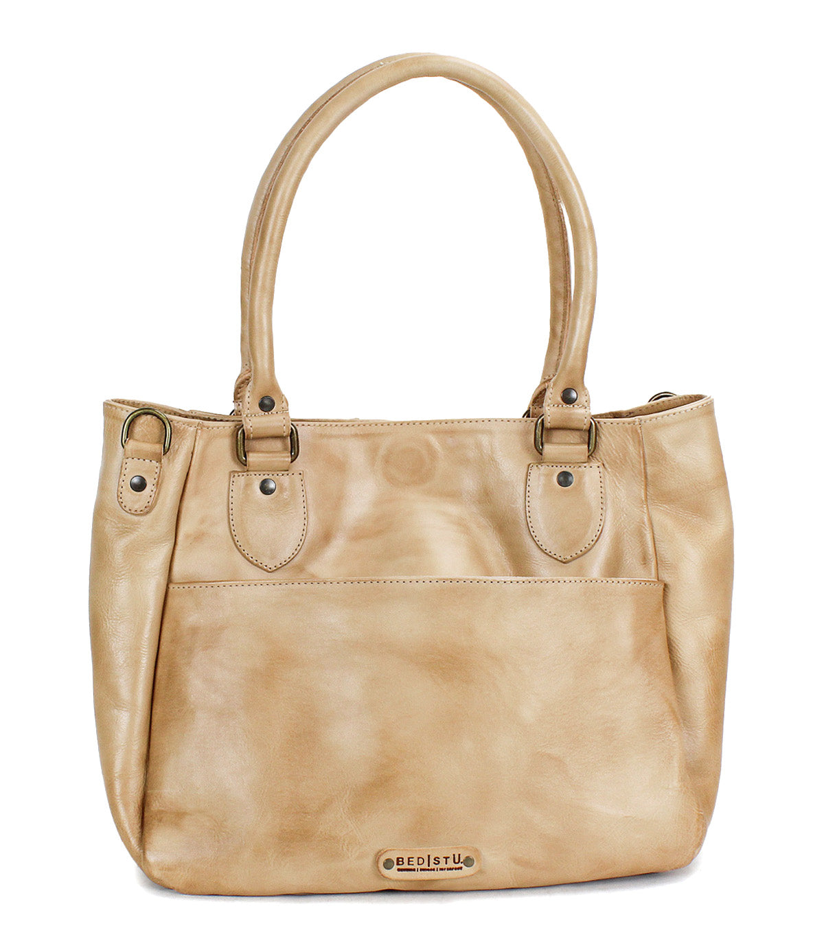 The Bed Stu Astana is a tan leather handbag featuring two handles, a front pocket, metal hardware, and a small brand logo on the bottom front—ideal for everyday use.