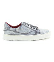 The Azeli by Bed Stu is a distressed light blue leather sneaker with a white sole and black laces, highlighted by a stitched 'X' design near the heel for a hint of classic style.