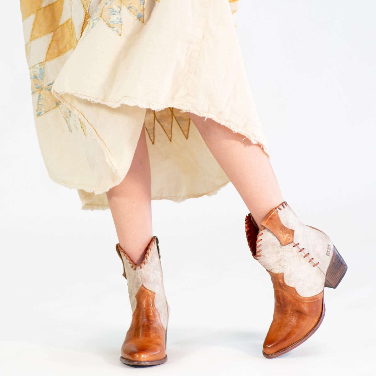 A woman in a dress and cowboy boots exudes Baila II cowgirl vibes from Bed Stu.
