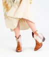 A woman in a dress and cowboy boots exudes Baila II cowgirl vibes from Bed Stu.
