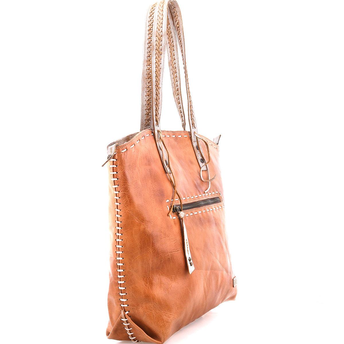 The Barra II by Bed Stu is a tan leather decorative tote with braided handles, woven edge stitching, and a front zippered pocket. It features an organic cotton lining and is shown on a white background.