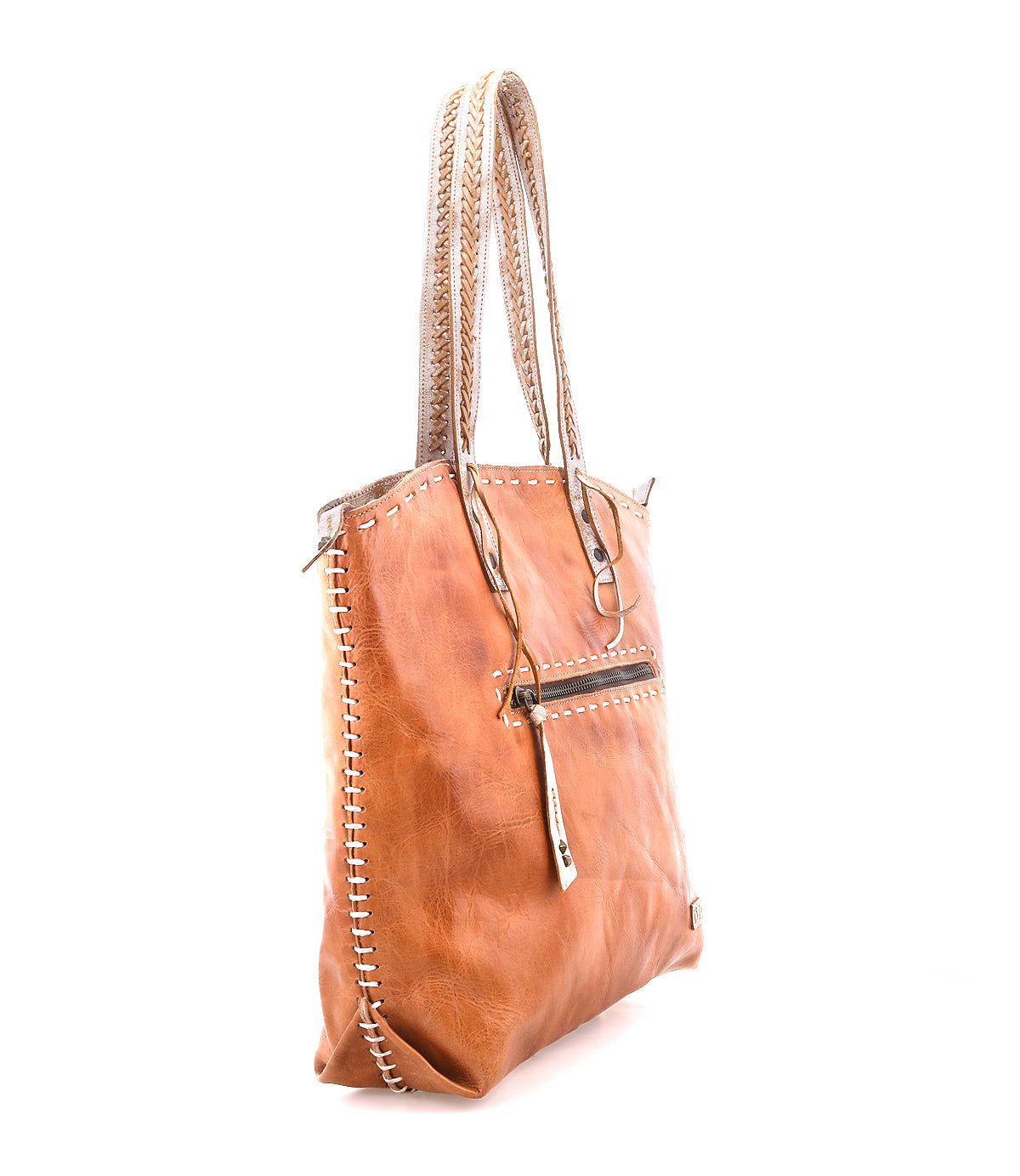 The Barra II by Bed Stu is a tan leather decorative tote with braided handles, woven edge stitching, and a front zippered pocket. It features an organic cotton lining and is shown on a white background.