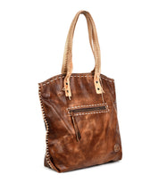 The Bed Stu Barra is a handmade leather tote bag featuring contrast stitching, a front zipper pocket, and two handles, shown on a white background.