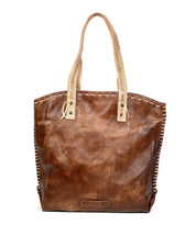 The Bed Stu Barra is a handmade leather tote bag with beige handles, eco-friendly finishes, and contrast stitching along the edges, shown standing upright on a white background.