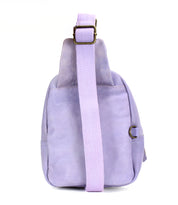 The Bed Stu Beau is a light purple leather sling backpack with a wide, durable strap, shown from the back against a white background—ideal for hands-free activities.