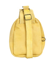 The Bed Stu Beau is a yellow leather sling backpack with a wide, durable strap, metal buckle, and side metal ring—ideal for hands-free activities. Shown against a white background.
