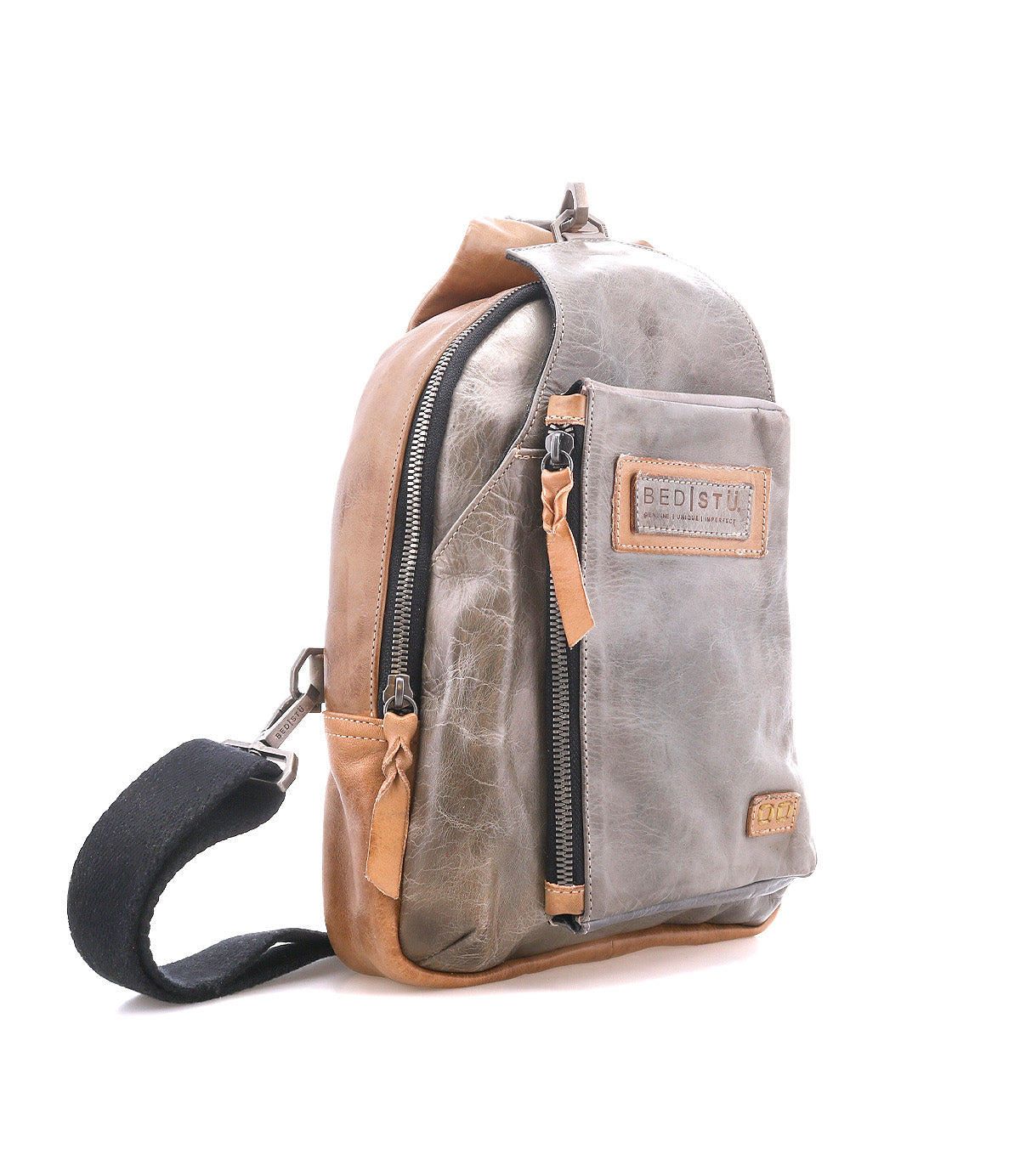 The Beau by Bed Stu is a small, two-tone leather sling backpack with front and main zippered compartments, a black adjustable strap, and a visible "BED|STU" patch—ideal for everyday use.