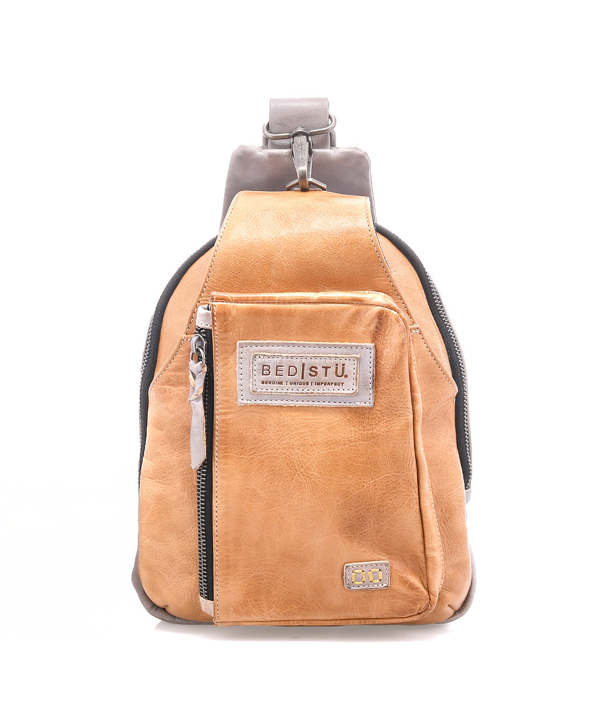 The Bed Stu "Beau" is a tan leather unisex sling backpack with a front zipper pocket, shown on a white background. Stylish and practical, it's perfect for everyday use.