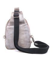 The Bed Stu Beau is a light gray leather sling backpack with an adjustable black strap and silver hardware, displayed from the back against a white background.