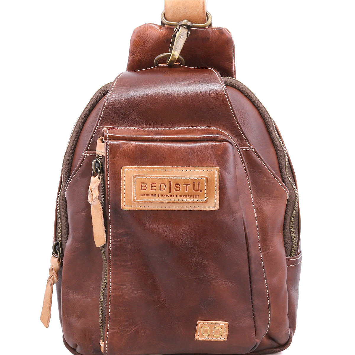 The Beau by Bed Stu is a small brown leather backpack featuring multiple zippered pockets and a tan label on the front. This stylish everyday bag keeps your essentials organized with classic sling versatility.