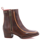 The Bed Stu Bitsy is a brown leather ankle boot with tan trim, side zipper, low stacked heel, square toe design, and a back pull tab.