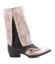 The Bed Stu Blind boot features a Western silhouette with a light tan shaft, decorative stitching, cut-out sides, a textured black foot, and a low angled heel.