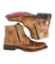 The Bed Stu Bonnie II is a pair of tan leather combat ankle boots featuring cap toes, side zippers, lace-up fronts, dark brown soles, and red tread on the bottom.