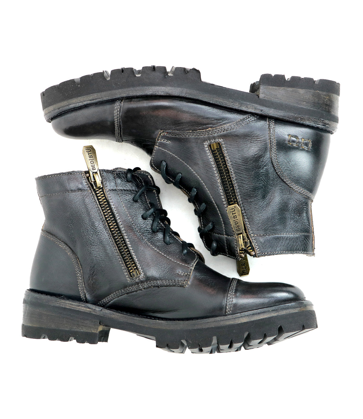 The Bed|Stü Bonnie IV is a pair of black leather combat boots featuring dual side zippers, classic laces, and rugged soles, photographed against a white background to highlight their secure fit and effortless style.