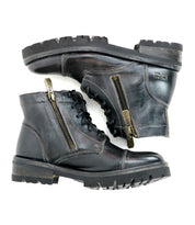 The Bed|Stü Bonnie IV is a pair of black leather combat boots featuring dual side zippers, classic laces, and rugged soles, photographed against a white background to highlight their secure fit and effortless style.