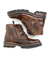 The Bed|Stü Bonnie IV is a pair of brown leather combat boots featuring dual side zippers, laces, and thick rubber soles for a secure fit, shown in a stacked side view.