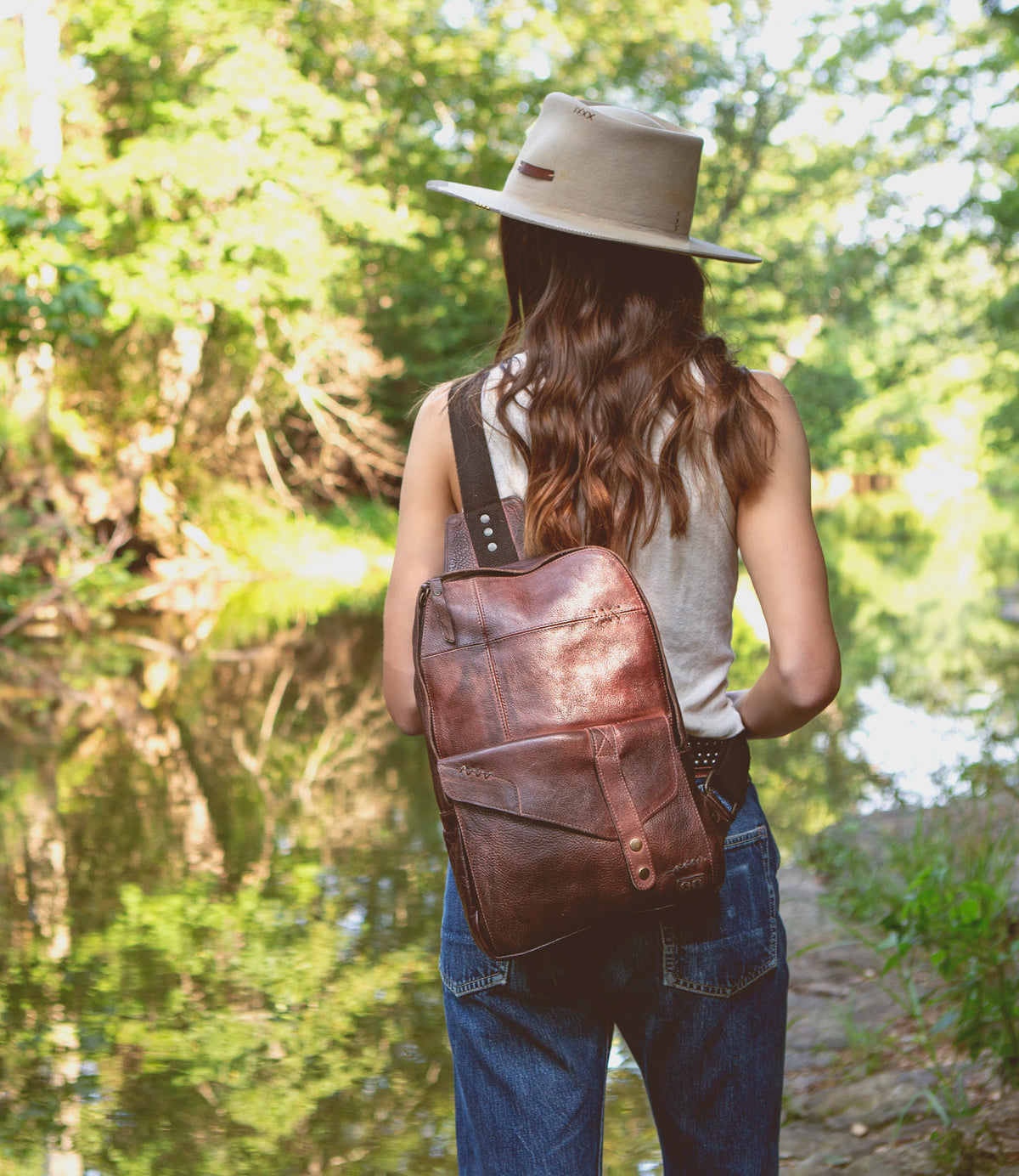 A durable woman wearing a Boss hat standing by a river. (brand name: Bed Stu)