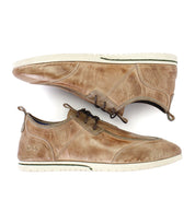 A pair of Bed|Stü Britches chukka-style casual shoes in refined brown leather with white soles, displayed side by side—one upright and the other lying on its side.