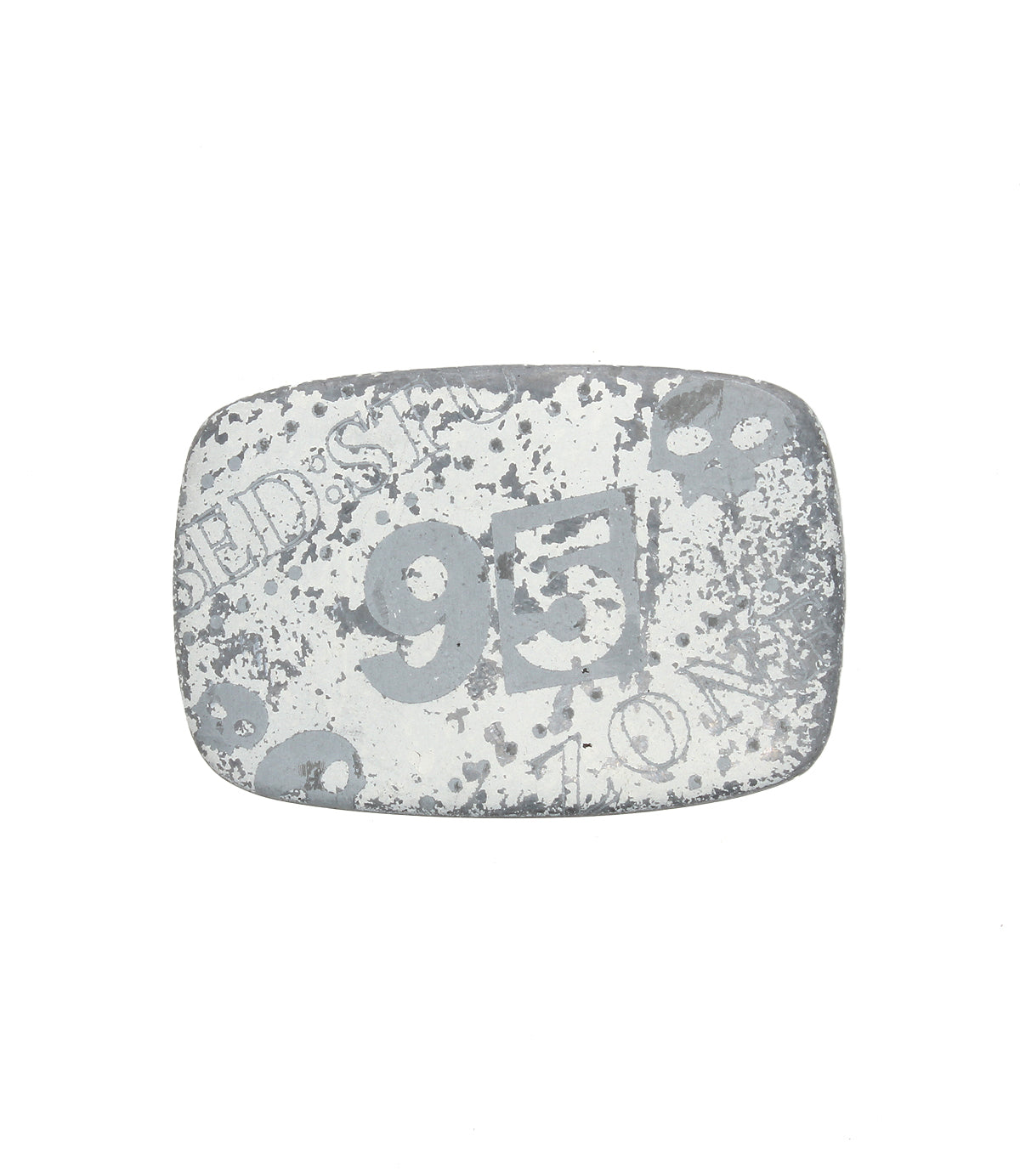 The Bed Stu 95 Buckle is a rectangular, weathered metal plate with a rugged look, featuring the faded number "95" and other markings on a white background.