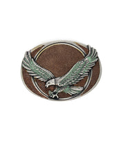 The Bed Stu Eagle B Buckle is an oval, vintage-style belt buckle featuring a raised eagle with outstretched wings in metallic tones on a brown textured background—a standout collector’s piece.