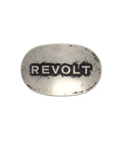 The Bed Stu Revolt Buckle is an oval, silver-tone belt buckle featuring the word "REVOLT" in bold, weathered black capital letters.