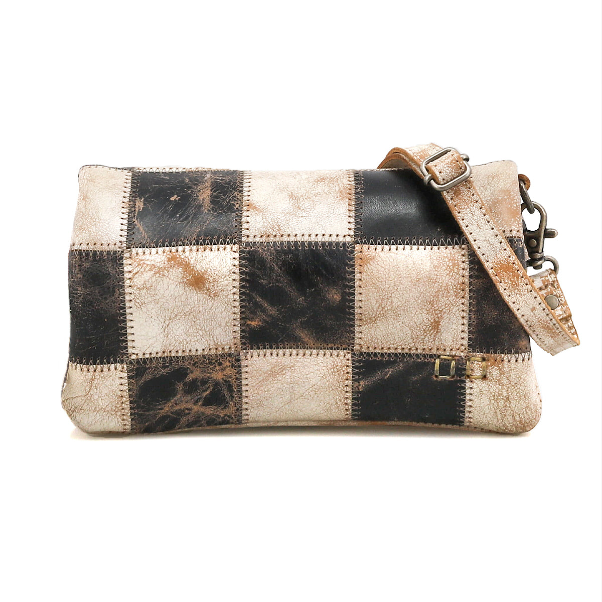 The Bed Stu Cadence PW is a rectangular crossbody bag featuring a patchwork of black and beige distressed leather squares and an adjustable strap.