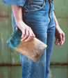 A woman in jeans holding a Bed Stu Cadence Speed, a versatile leather clutch featuring an embroidered star.