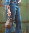 A woman in jeans holding a Bed Stu Cadence Speed brown leather purse.