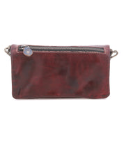 The Cadence by Bed Stu is a rectangular, dark brown crossbody clutch crafted from vegetable-tanned leather, featuring a top zipper and metal clip attachments on both sides.