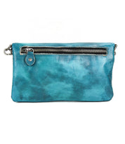 The Bed Stu Cadence is a teal leather wallet clutch with a front zipper pocket and metal hardware, shown against a white background.