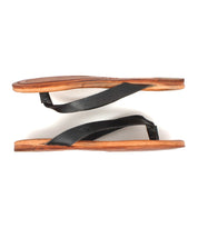 The Bed Stu Calma sandals feature black leather straps and brown flat soles, shown in a side view on a white background—a lightweight and comfortable choice for relaxing.