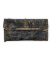 The Canton by Bed Stu is a clutch-style wallet made from worn, dark leather with a flap cover, lying flat on a white background.