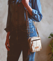 A woman wearing a denim shirt holding a Bed Stu Capture handcrafted cross body bag.