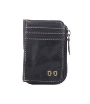 The Carrie wallet by Bed|Stü is a small, black compact leather accessory featuring white stitching, gold metal accents, three easy-access card slots, and a zippered side compartment, shown against a white background.
